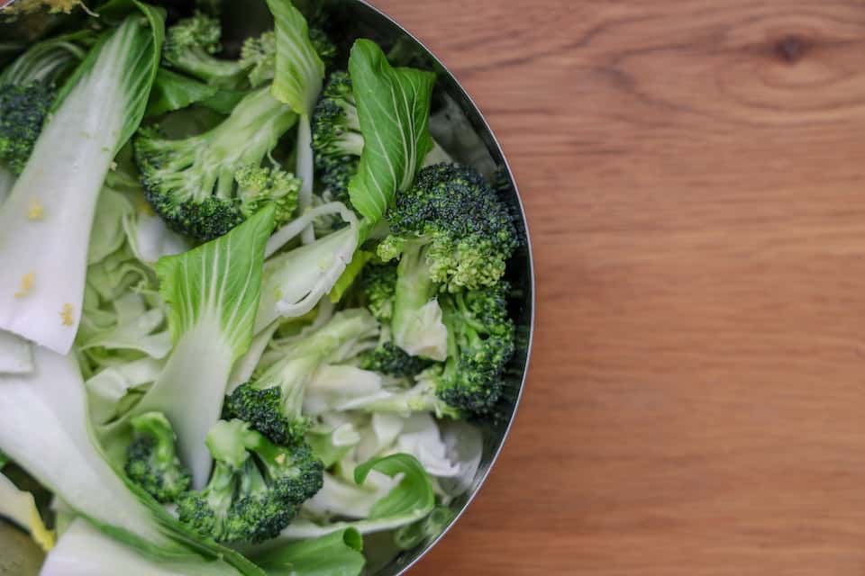 Bok choy and broccoli in a black bowl