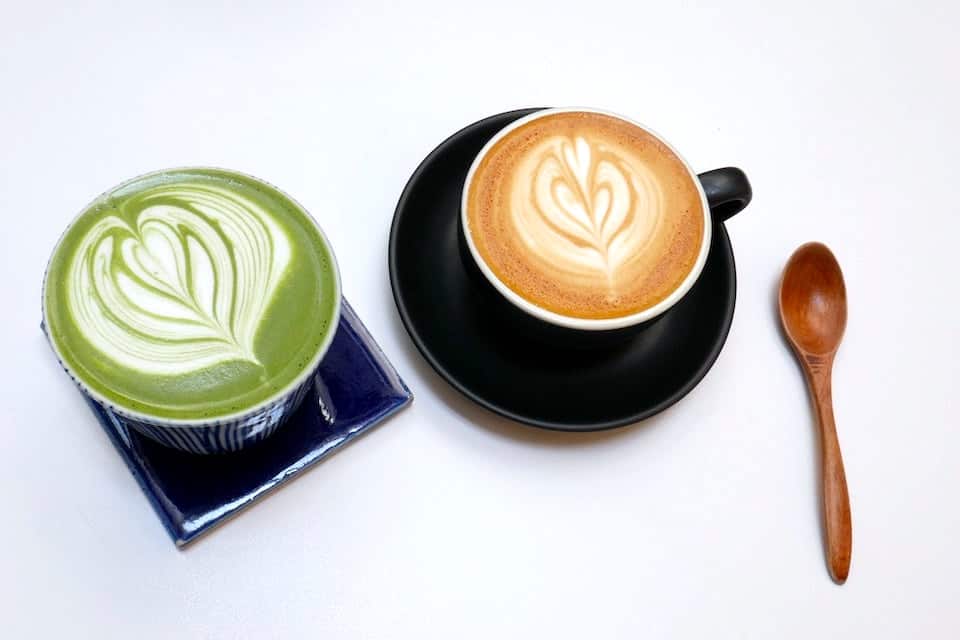 A matcha tea latte next to a regular espresso-based latte