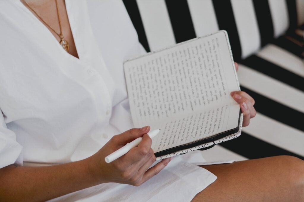 A woman practises gratitude journaling while writing her thoughts in a notebook.