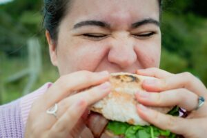 A woman biting into a sandwhich