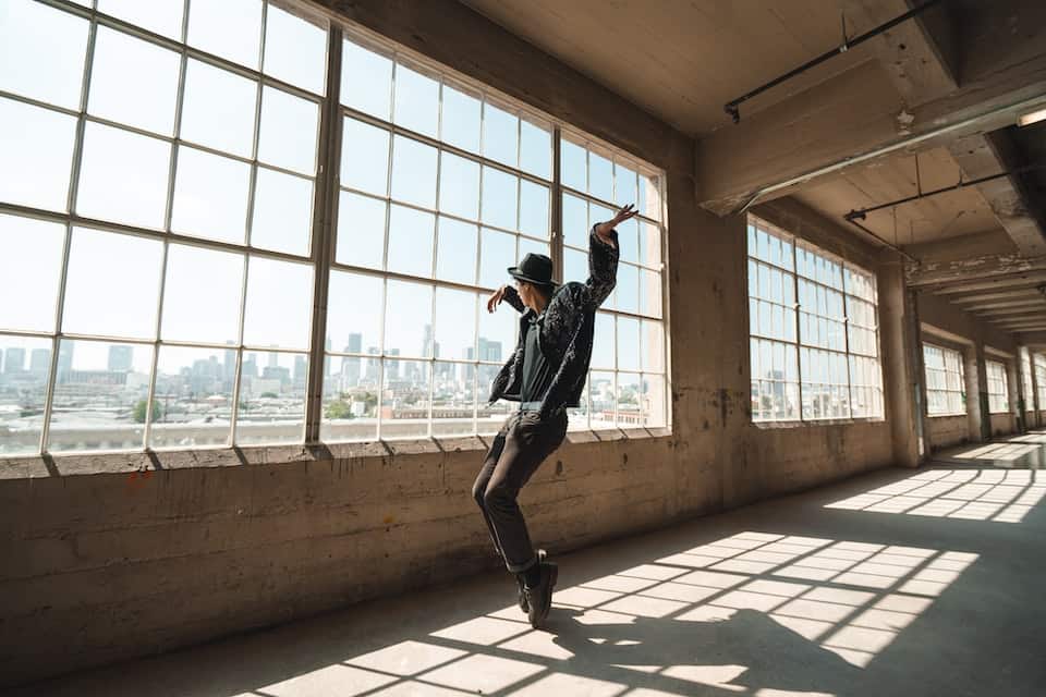 A man dances next to industrial looking windows
