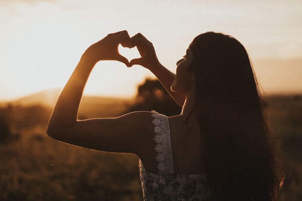 A woman holds up her hands in the shape of a heart