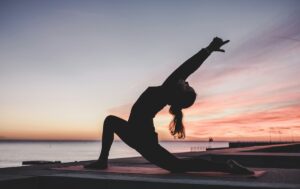 A woman doing yoga in front of a sunset