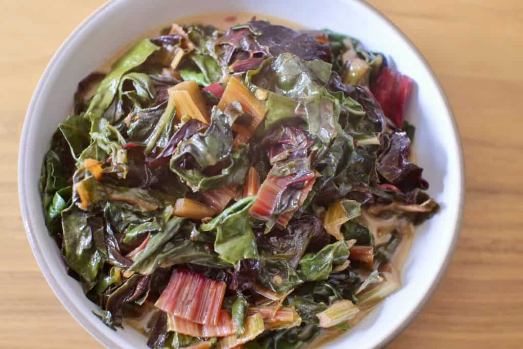 A bowl filled with braised leafy greens in coconut milk