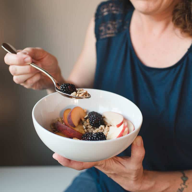 Woman eating a bowl of oatmeal and fruit
