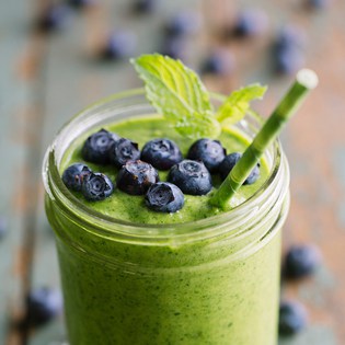 A green smoothie topped with blueberries